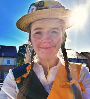 Chloe in her Sheffield University Morris hat and kit, smiling at the camera